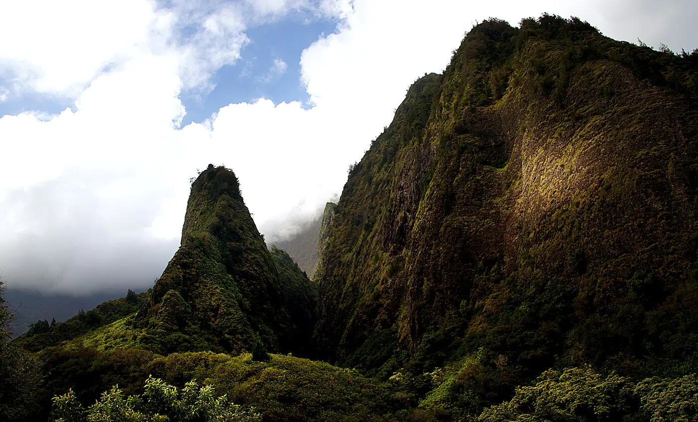 The ʻĪao Needle rising beside sheer green ridges in ʻĪao Valley