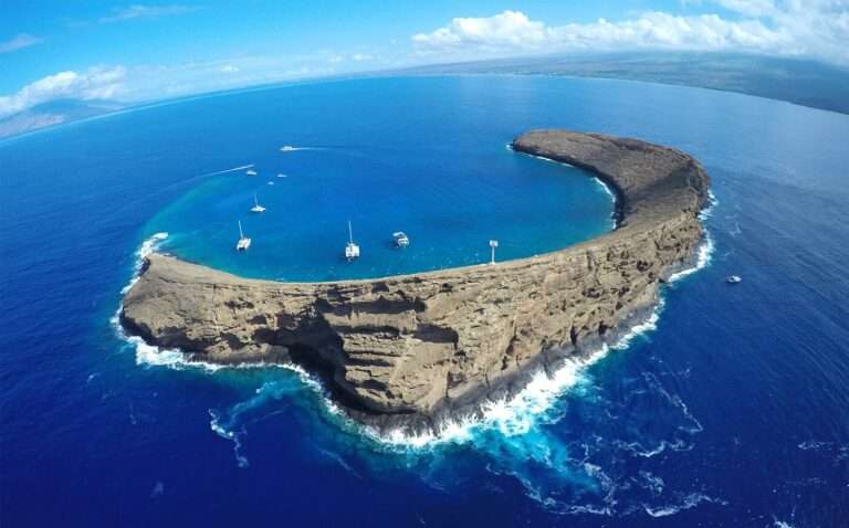 Aerial view of Molokini's crescent rim with snorkel boats anchored in the clear crater water